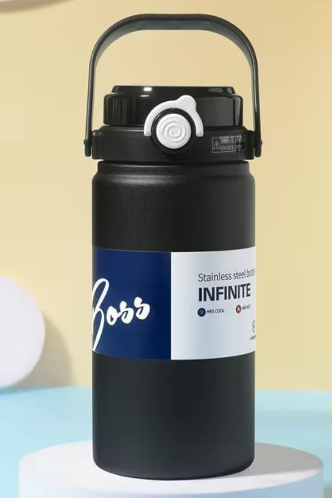 Black water bottle with a label on a light blue surface and beige background